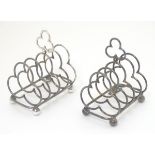 A pair of silver plate toast racks with 5 divisions of trefoil form and central handle.