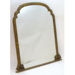 A late 19thC carved overmantle mirror with a shaped frame decorated with foliate detailing.
