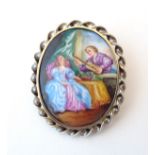 A silver gilt brooch set with hand painted ceramic cabochon depicting a 19thC interior scene.