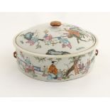 A Chinese lidded pot decorated with figures in a garden with flowers, fruit, vases etc.