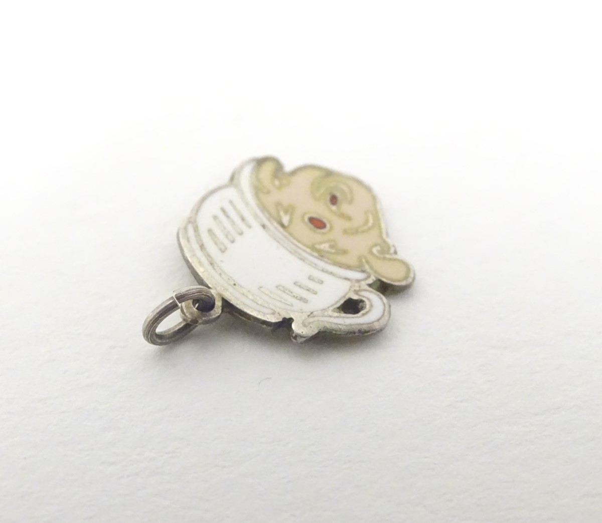 A mid 20thC novelty white metal pendant charm formed as a humorous face wearing a chamber pot as a - Image 3 of 5