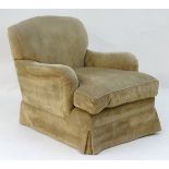 A Howard and Sons style armchair with shaped backrest, drop in seat and low hanging trim.