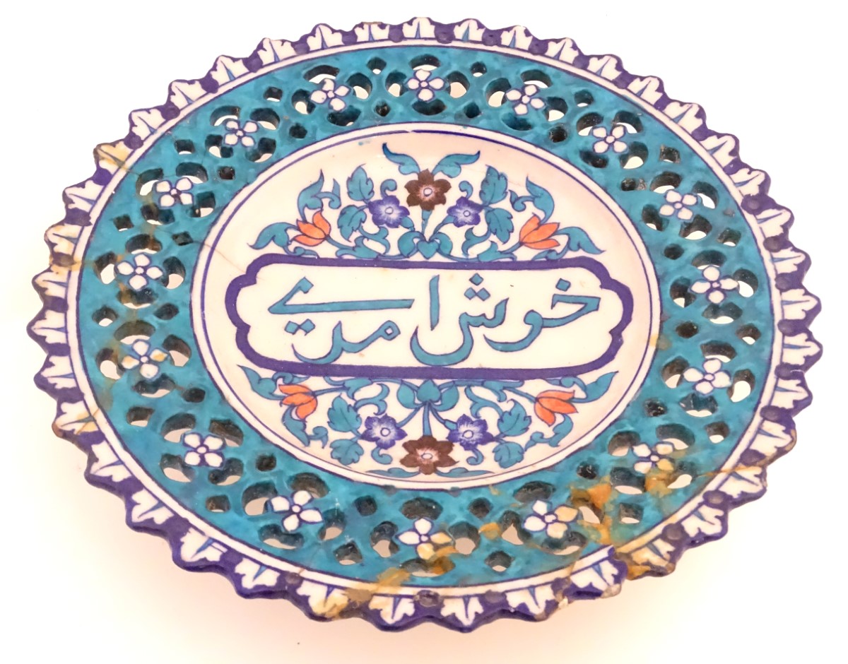 A 19thC Persian dish with Islamic script to the centre surrounded by stylised flowers and foliage,