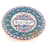A 19thC Persian dish with Islamic script to the centre surrounded by stylised flowers and foliage,