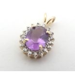 A 14kt gold pendant set with central amethyst bordered by diamonds approx 1/2" long Please Note - we
