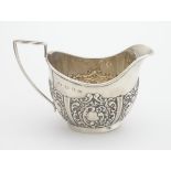 A silver cream jug with repousse decoration. Hallmarked Birmingham 1898 maker George Unite. 3"