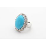 An 18ct white gold ring set with central turquoise cabochon bordered by diamonds. the cabochon