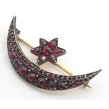 A 19thC yellow metal brooch of crescent moon and star shape and set with a profusion of garnets. 1