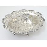 A silver dish with punch, pierced and embossed decoration and standing on four feet. Hallmarked