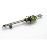 A white metal bar brooch set with spider to centre set with green stones. 2 ¼'' long. Please