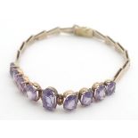 A yellow metal bracelet set with 9 graduated semi-precious blue/purple stones. ( unmarked however