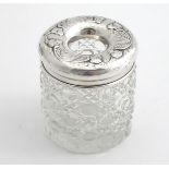 A cut glass dressing table jar / hair tidy with embossed cherub decoration. Hallmarked Chester
