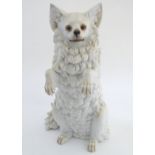 A German porcelain seated dog with a detailed face and inset glass eyes. Marked under. Approx. 10