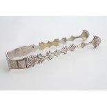 19thC silver sugar tongs with cast and engraved delectation. Indistinctly marked 5 1/4" long (38g)