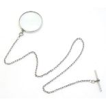A magnifying glass mounted on a silver and white metal Albert chain. The glass approx 2" diameter,