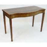 An early 19thC mahogany serving table with a serpentine shaped front, crossbanded top and having