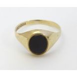 A 9ct gold and onyx signet ring. Approx. size M 1/2 Please Note - we do not make reference to the