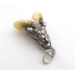 A hunting trophy pendant set with a deers tooth within a white metal mount with oak leaf and acorn