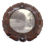 A 20thC circular carved mahogany frame of stylised wreath form, displaying a black and white