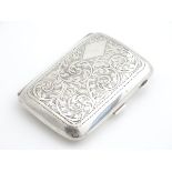 A silver cigarette case with engraved acanthus scroll decoration and gilded interior. Hallmarked