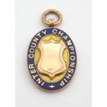 A 9ct gold fob medal with enamelled Inter County Championship emblem. Total weight 18g Please Note -