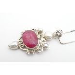 A silver peandt set with pearls and red stone. The pendant 2" long with a chain 20" long Please Note