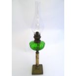 An early 20thC oil lamp, the green glass reservoir supported by an onyx and brass column and base,