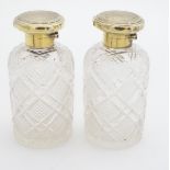 A pair of cut glass scent flasks / bottles with silver gilt tops with engine turned decoration.