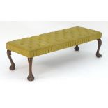 An early 20thC footstool with deep buttoned upholstery above four cabriole legs terminating in