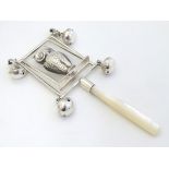 A white metal children's rattle with owl decoration, bells and mother of pearl teether. 5" long