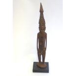 A tribal wooden carving of a male figure with a mask and headdress from the Sepik River region,