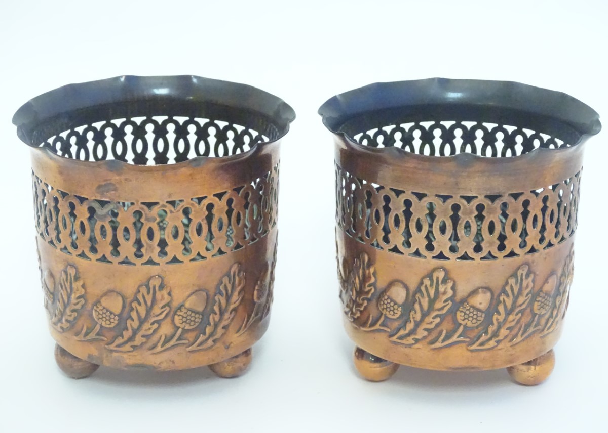 A pair of small copper planters with lobed rims, decorative reticulated banding and embossed acorn