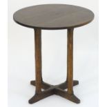 An early / mid 20thC oak Cotswold school occasional table with a circular table top above canted