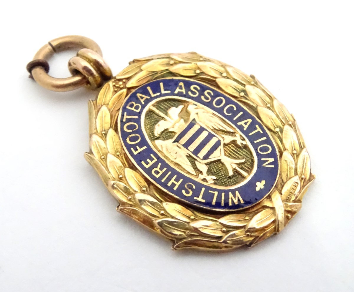 A 9ct gold fob medal with enamelled Wiltshire Football Association emblem. Total weight 8g Please