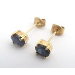 A pair of yellow metal stud earrings set with oval cut blue stones. Approx 1/4" long Please Note -