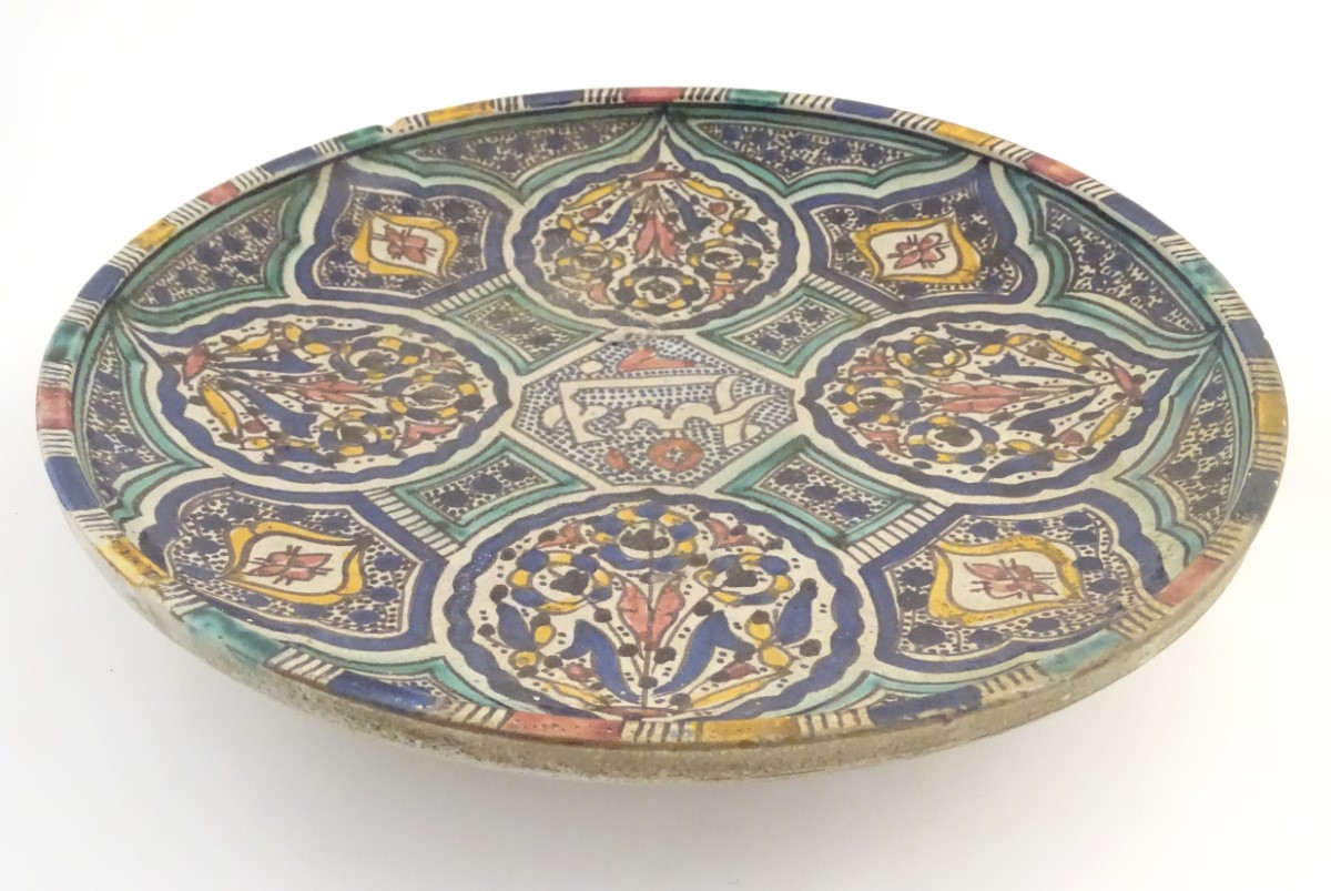 A Moroccan charger with panelled geometric designs with lotus and leaf shaped cartouches with