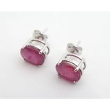 A pair of 18ct white gold stud earrings set with oval rubies. Please Note - we do not make reference