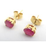 A pair of gilt metal stud earrings set with red stones. Please Note - we do not make reference to