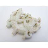 A carved jade pendant / toggle depicting stylised animals with engraved detail. Approx. 3" x 3 1/