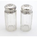 A pair of glass dressing table jars with silver tops having hammered decoration and shield