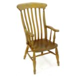 An early 20thC lathe back open armchair with an elm seat, scrolled arms and standing on turned