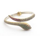 A silver bangle formed bracelet of snake form set with white red and green paste stones. Please Note