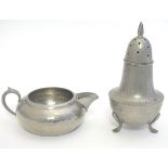 An Arts & Crafts hammered pewter sugar caster raised on three feet, and a hammered pewter milk