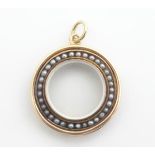 A Victorian 9ct gold and gilt metal locket of circular form with central glazed locket section