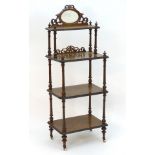 A Victorian walnut four tier whatnot with a mirrored gallery and fretwork decoration, having