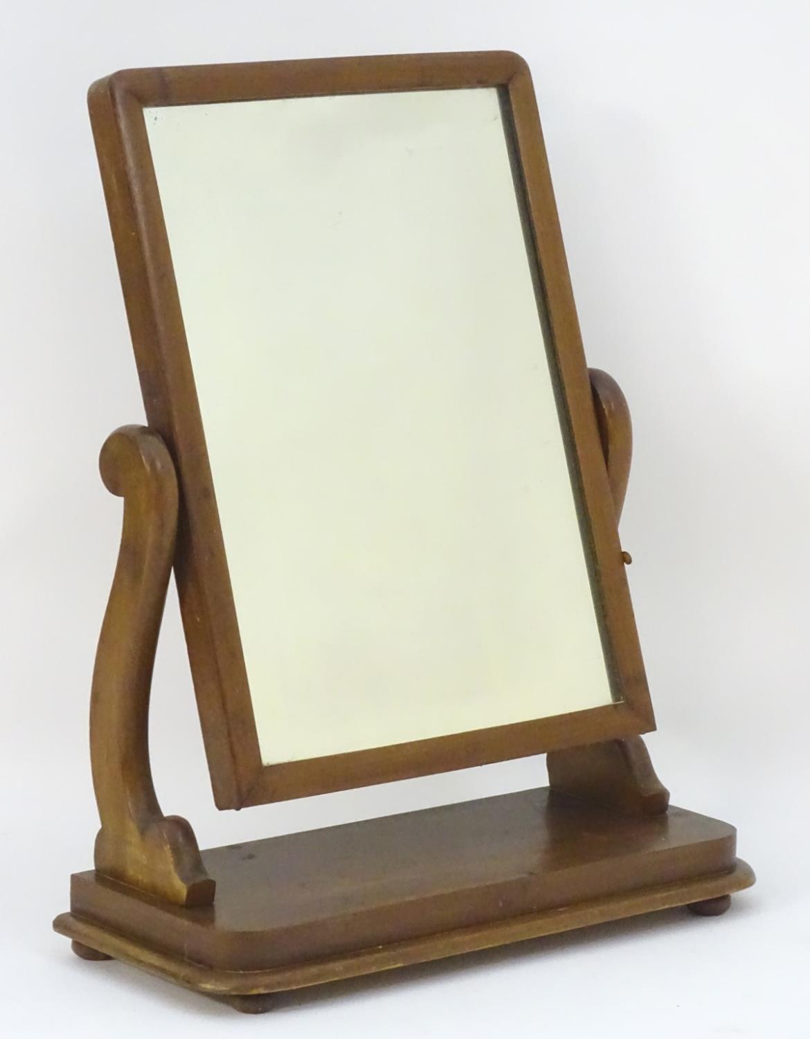 An early / mid 19thC mahogany toilet / dressing mirror with scrolled supports and a rectangular