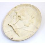 A marble / composite oval wall plaque with a relief depiction of a Victorian woman in profile.