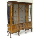 A 20thC mahogany display cabinet with a foliate carved cornice and frieze above a central astragal