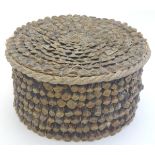A naive circular box decorated with layered pine cone scales. Approx. 4 1/4" high x 8" diameter.