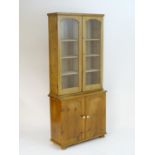 An early 20thC pine bookcase with a moulded cornice above two glazed doors, the base comprising